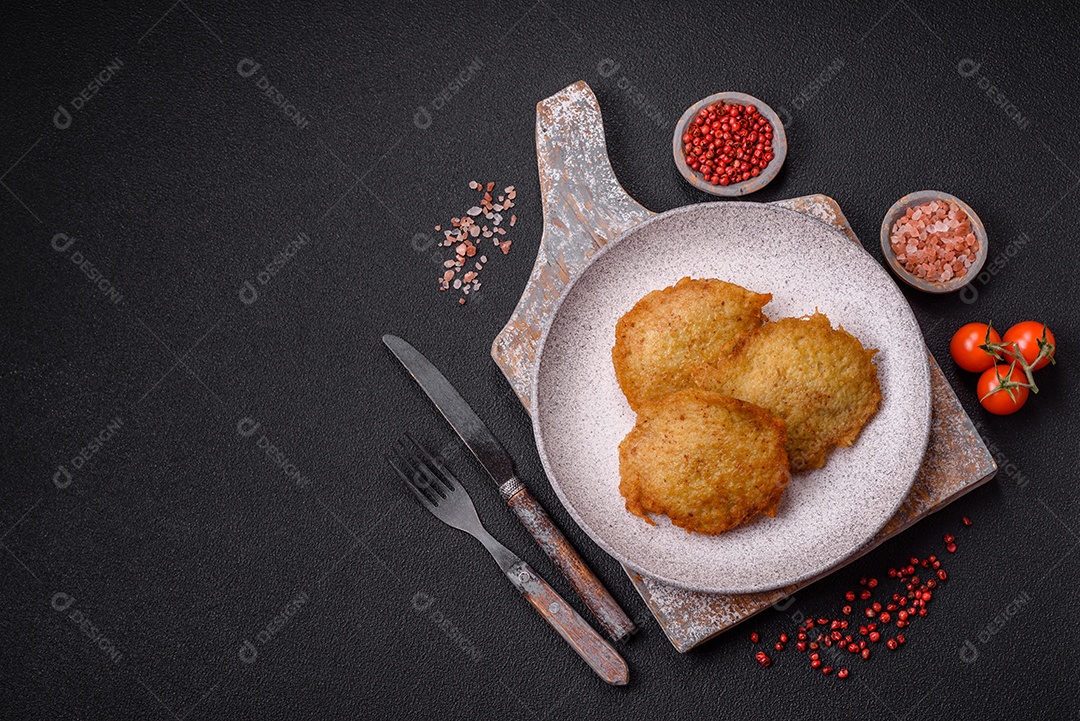 Deliciosas panquecas crocantes feitas de batatas, carne, cenouras, cebolas com sal, especiarias e ervas sobre um fundo escuro de concreto