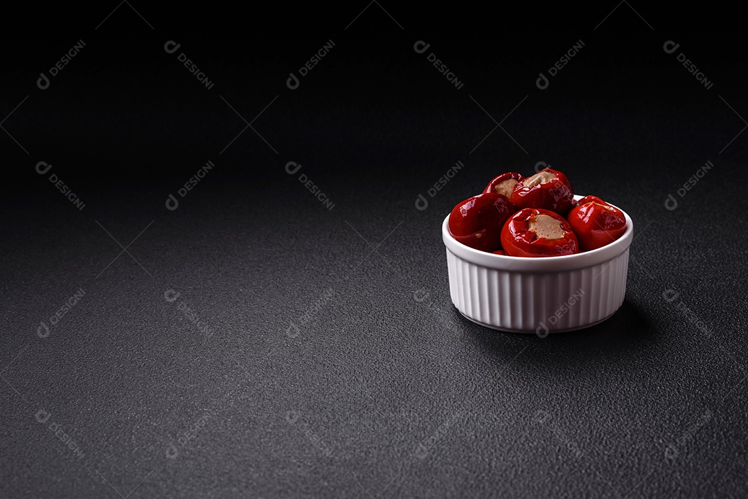 Pimentões vermelhos recheados com queijo ou carne com sal, especiarias e ervas num prato de cerâmica