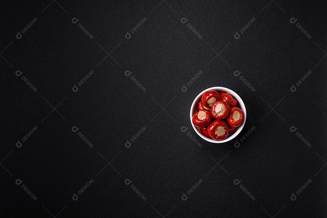 Pimentões vermelhos recheados com queijo ou carne com sal, especiarias e ervas num prato de cerâmica