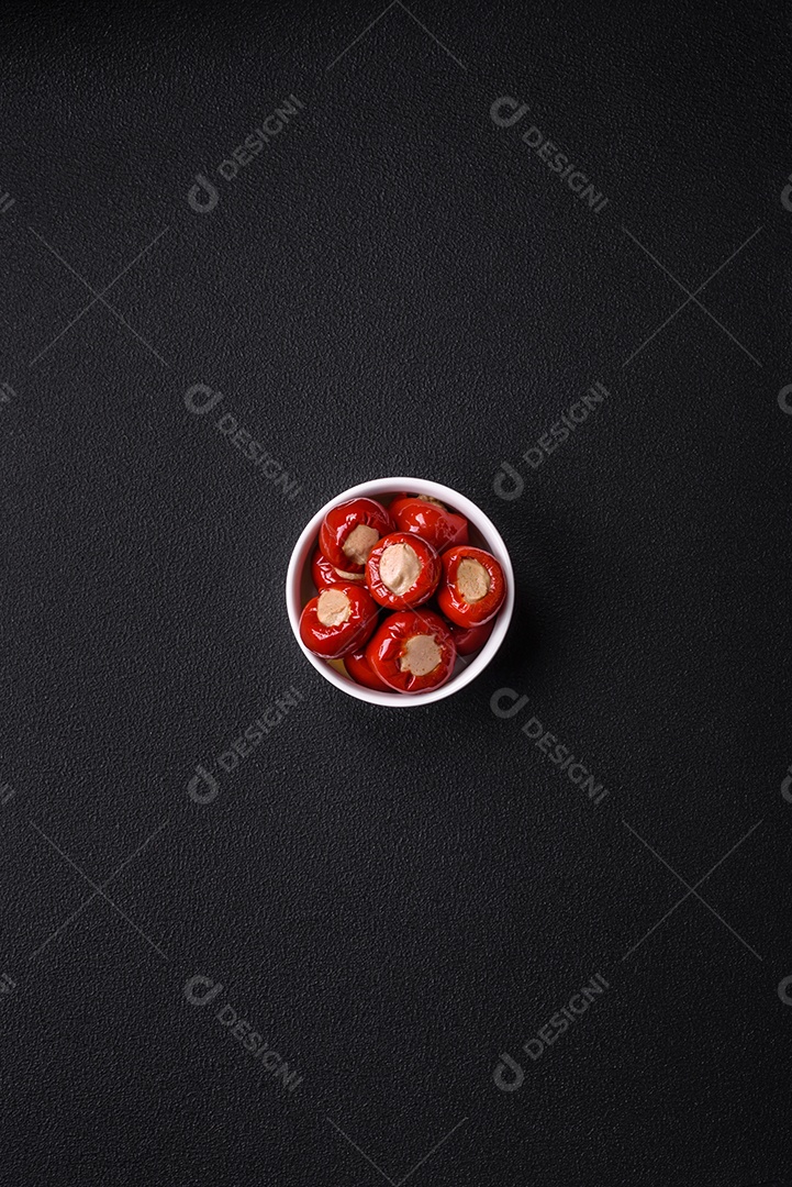 Pimentões vermelhos recheados com queijo ou carne com sal, especiarias e ervas num prato de cerâmica