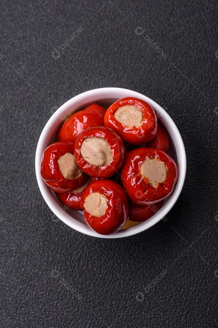 Pimentões vermelhos recheados com queijo ou carne com sal, especiarias e ervas num prato de cerâmica