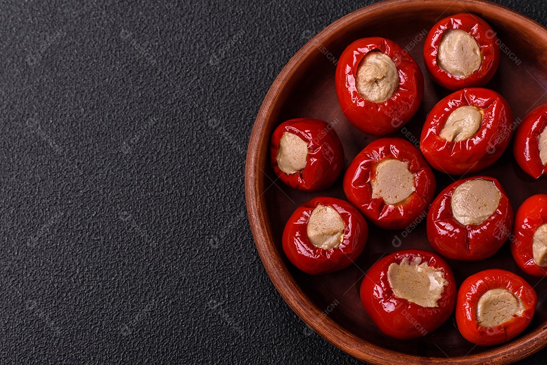 Pimentões vermelhos recheados com queijo ou carne com sal, especiarias e ervas num prato de cerâmica