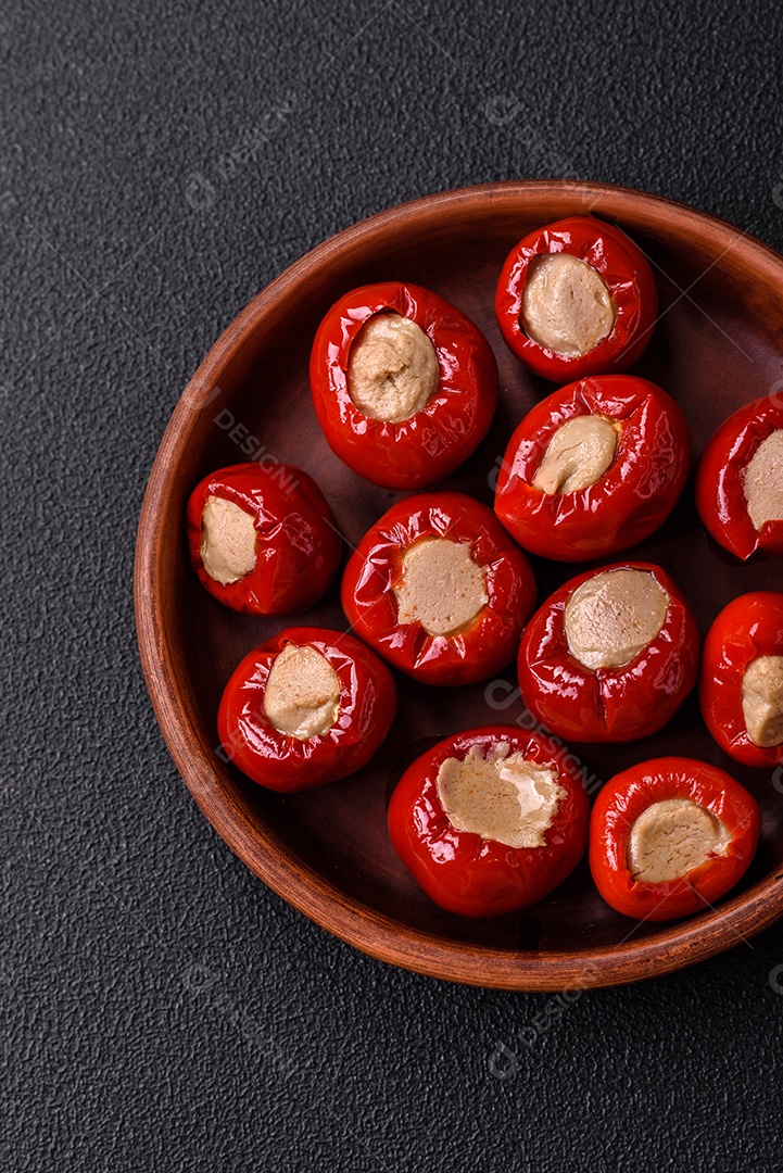 Pimentões vermelhos recheados com queijo ou carne com sal, especiarias e ervas num prato de cerâmica