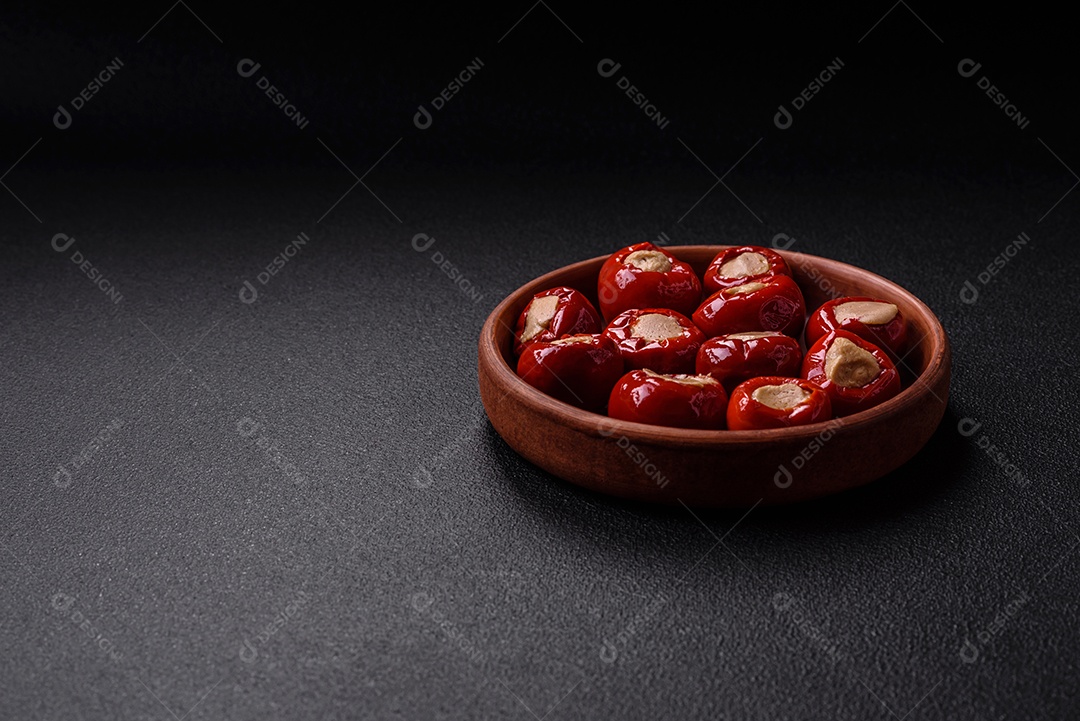 Pimentões vermelhos recheados com queijo ou carne com sal, especiarias e ervas num prato de cerâmica