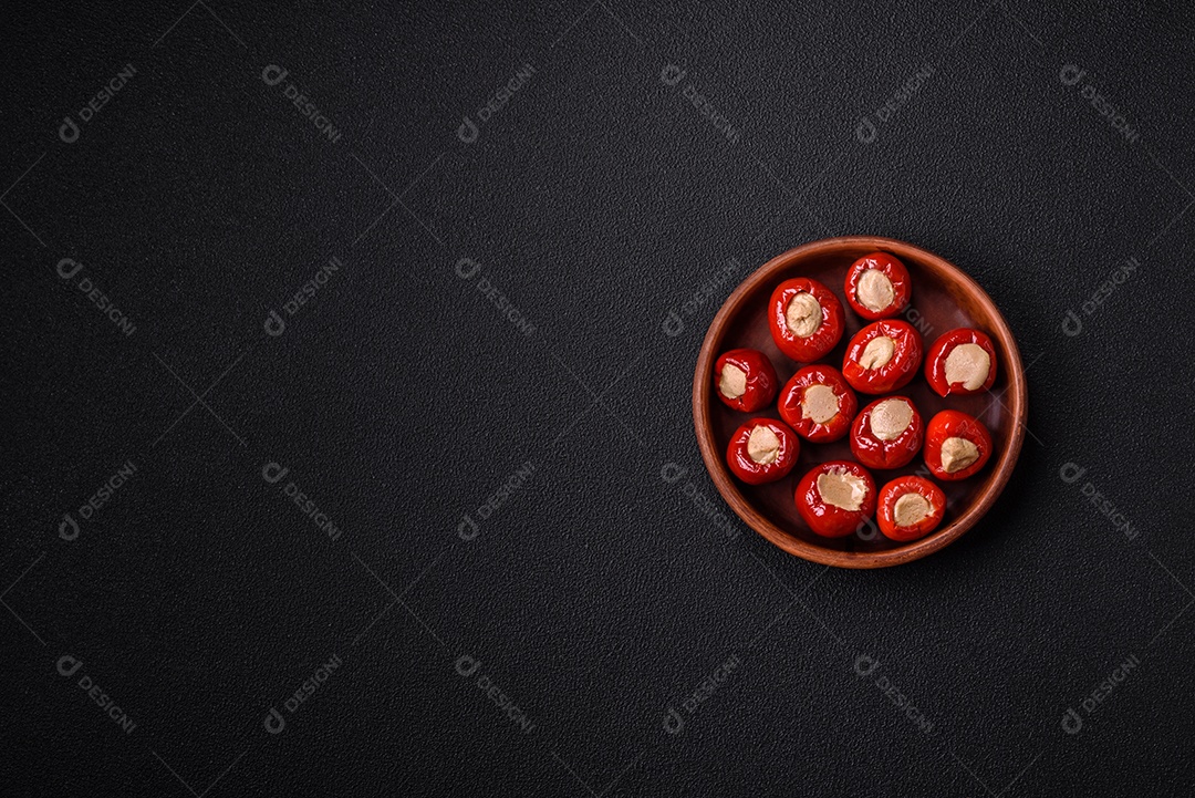 Pimentões vermelhos recheados com queijo ou carne com sal, especiarias e ervas num prato de cerâmica