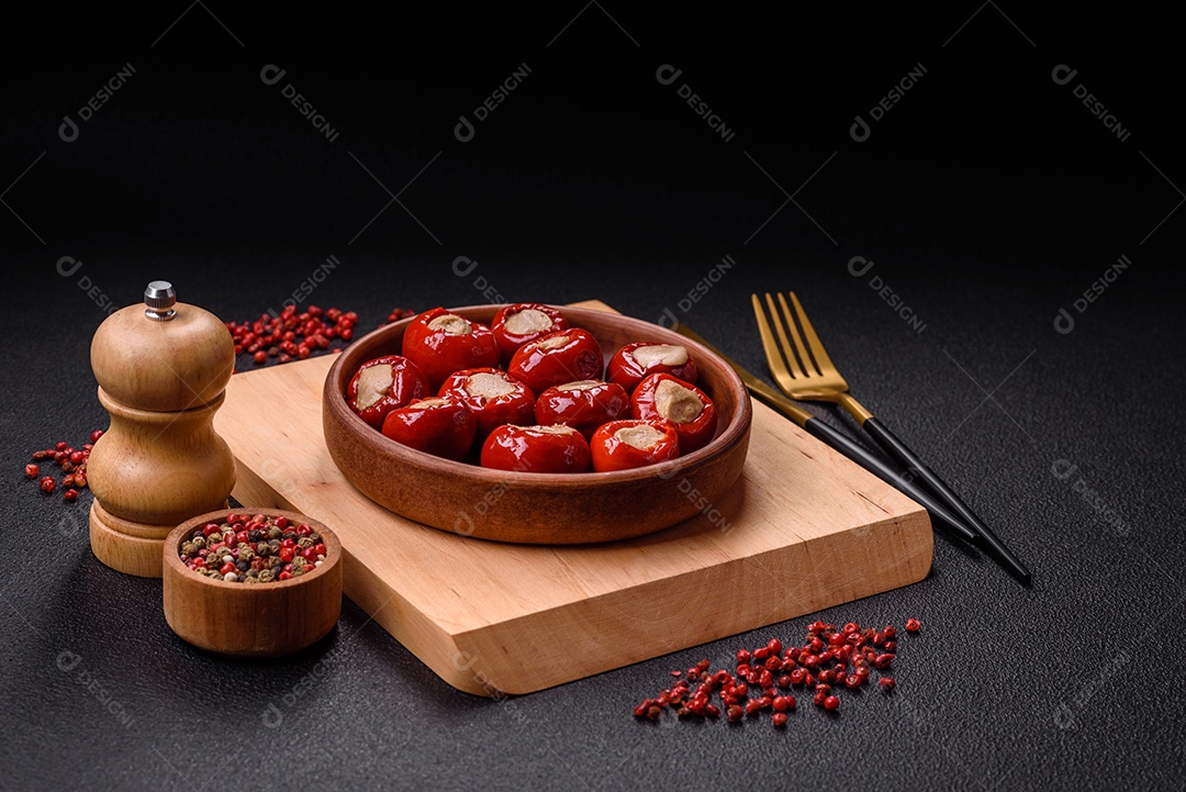 Pimentões vermelhos recheados com queijo ou carne com sal, especiarias e ervas num prato de cerâmica