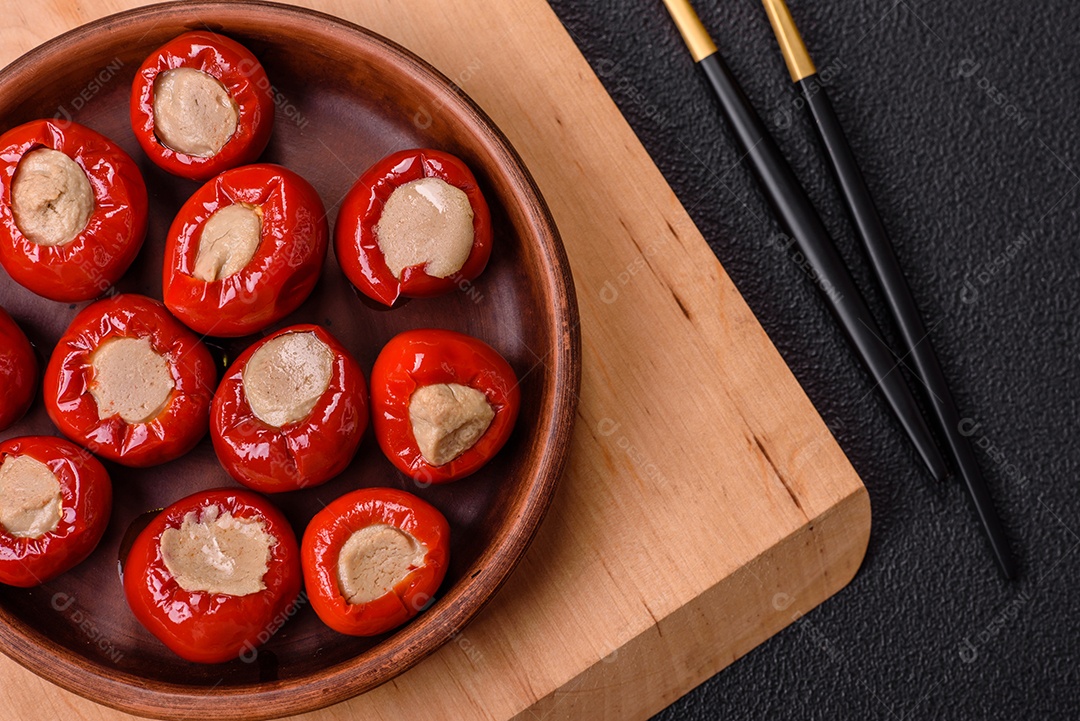 Pimentões vermelhos recheados com queijo ou carne com sal, especiarias e ervas num prato de cerâmica
