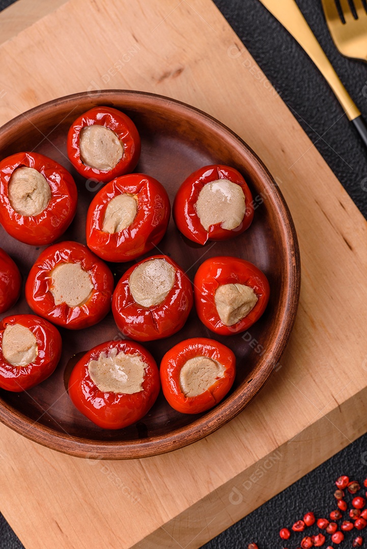 Pimentões vermelhos recheados com queijo ou carne com sal, especiarias e ervas num prato de cerâmica