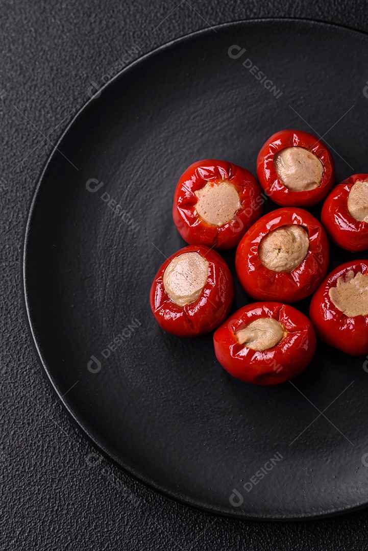 Pimentões vermelhos recheados com queijo ou carne com sal, especiarias e ervas num prato de cerâmica