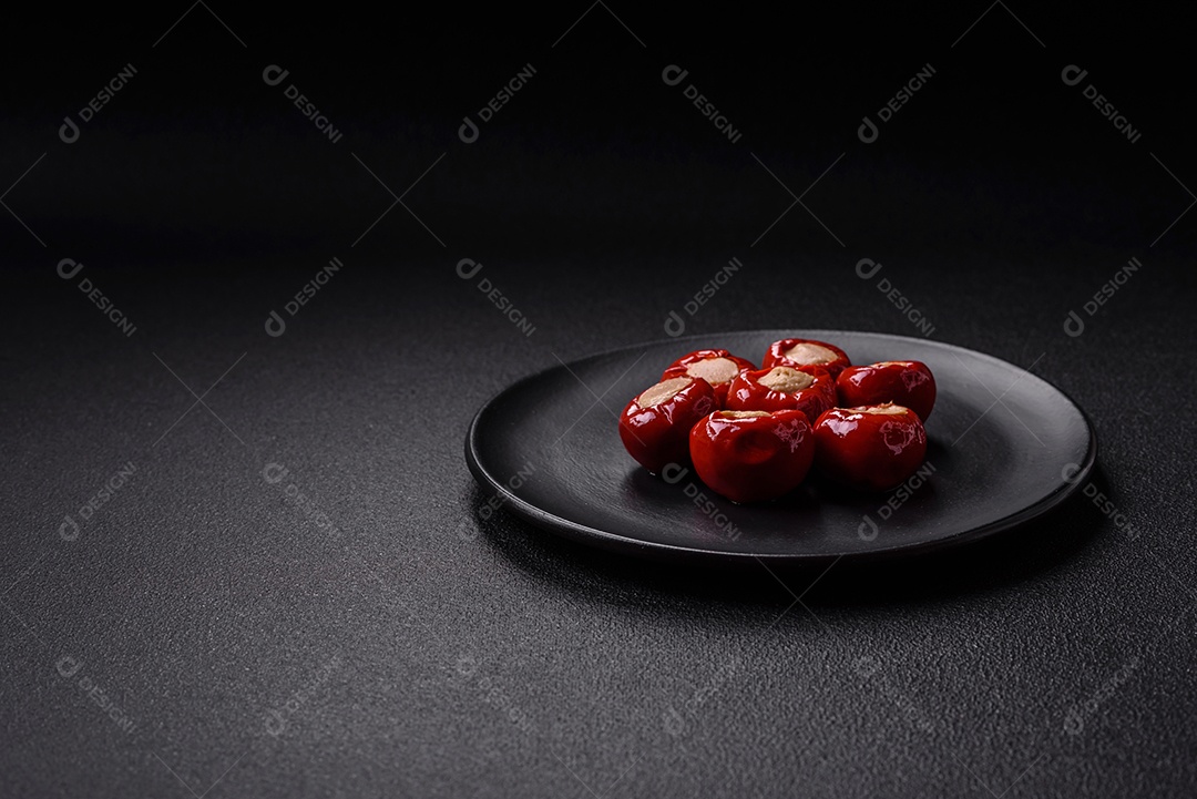 Pimentões vermelhos recheados com queijo ou carne com sal, especiarias e ervas num prato de cerâmica