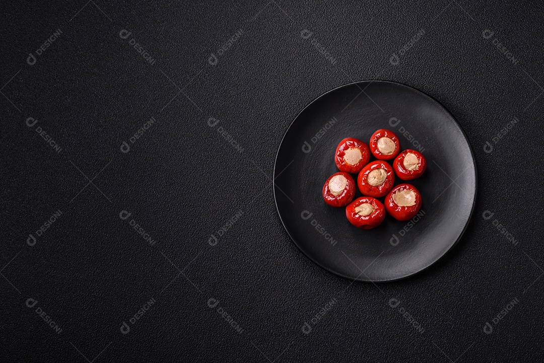 Pimentões vermelhos recheados com queijo ou carne com sal, especiarias e ervas num prato de cerâmica