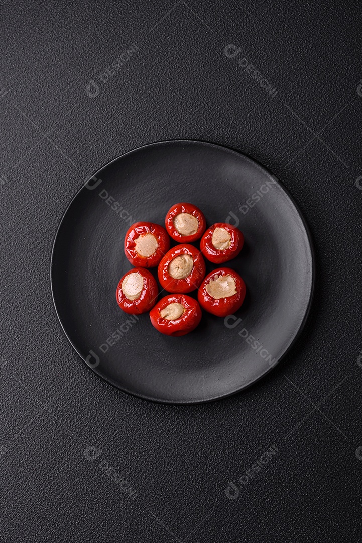 Pimentões vermelhos recheados com queijo ou carne com sal, especiarias e ervas num prato de cerâmica