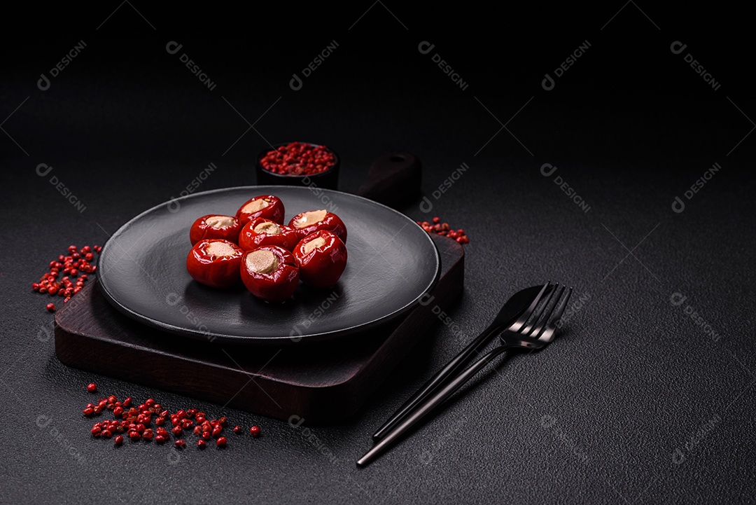 Pimentões vermelhos recheados com queijo ou carne com sal, especiarias e ervas num prato de cerâmica