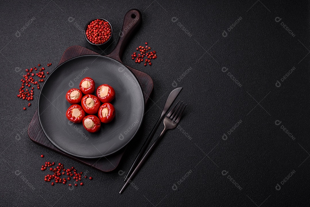 Pimentões vermelhos recheados com queijo ou carne com sal, especiarias e ervas num prato de cerâmica