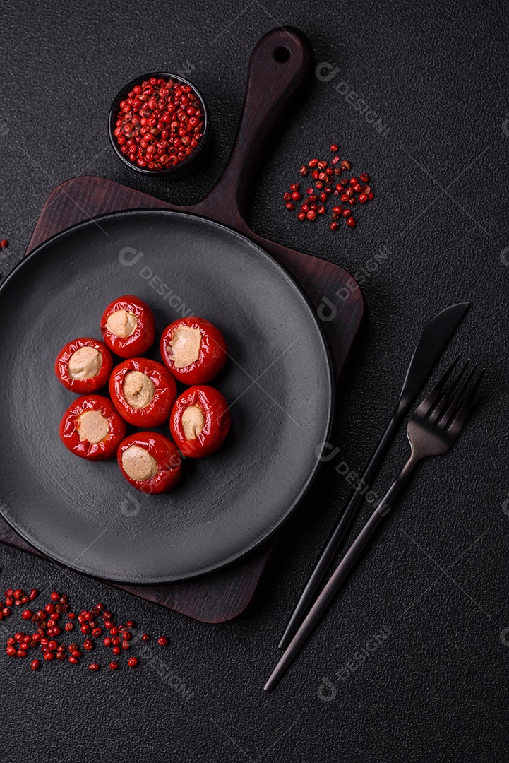 Pimentões vermelhos recheados com queijo ou carne com sal, especiarias e ervas num prato de cerâmica