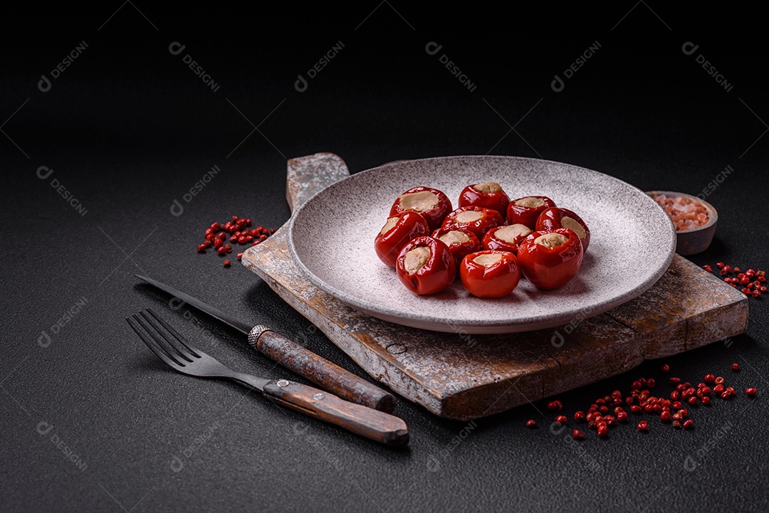 Pimentões vermelhos recheados com queijo ou carne com sal, especiarias e ervas num prato de cerâmica