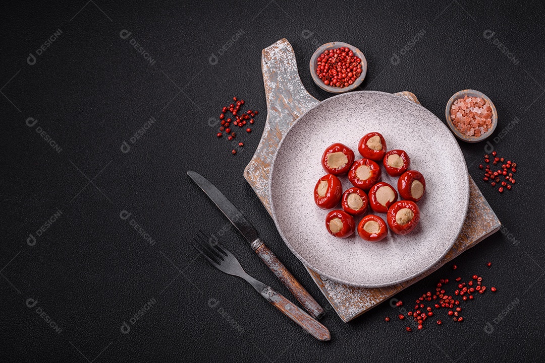 Pimentões vermelhos recheados com queijo ou carne com sal, especiarias e ervas num prato de cerâmica