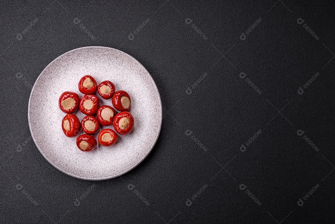 Pimentões vermelhos recheados com queijo ou carne com sal, especiarias e ervas num prato de cerâmica