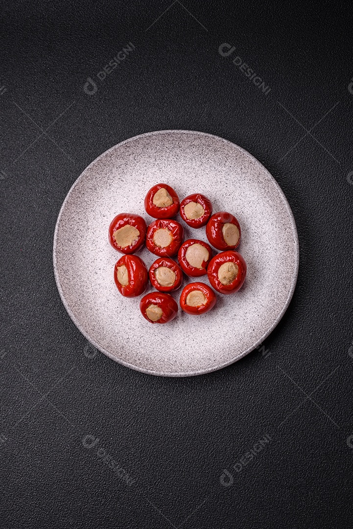 Pimentões vermelhos recheados com queijo ou carne com sal, especiarias e ervas num prato de cerâmica