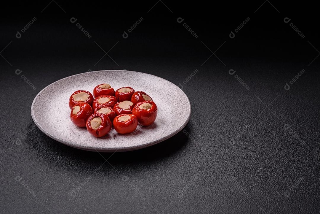 Pimentões vermelhos recheados com queijo ou carne com sal, especiarias e ervas num prato de cerâmica
