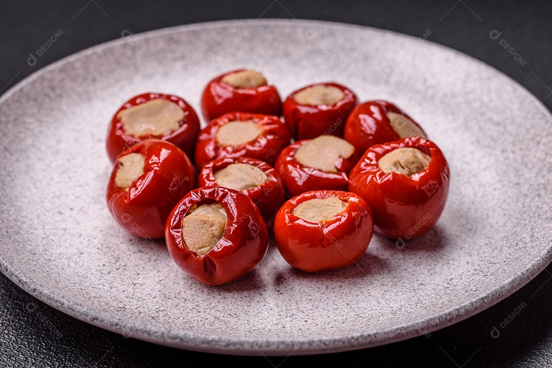 Pimentões vermelhos recheados com queijo ou carne com sal, especiarias e ervas num prato de cerâmica