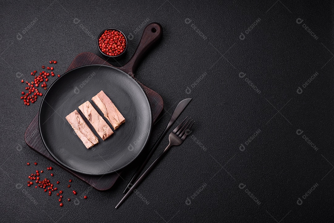 Deliciosa carne de atum dietético enlatado com sal, especiarias e óleo sobre um fundo escuro de concreto