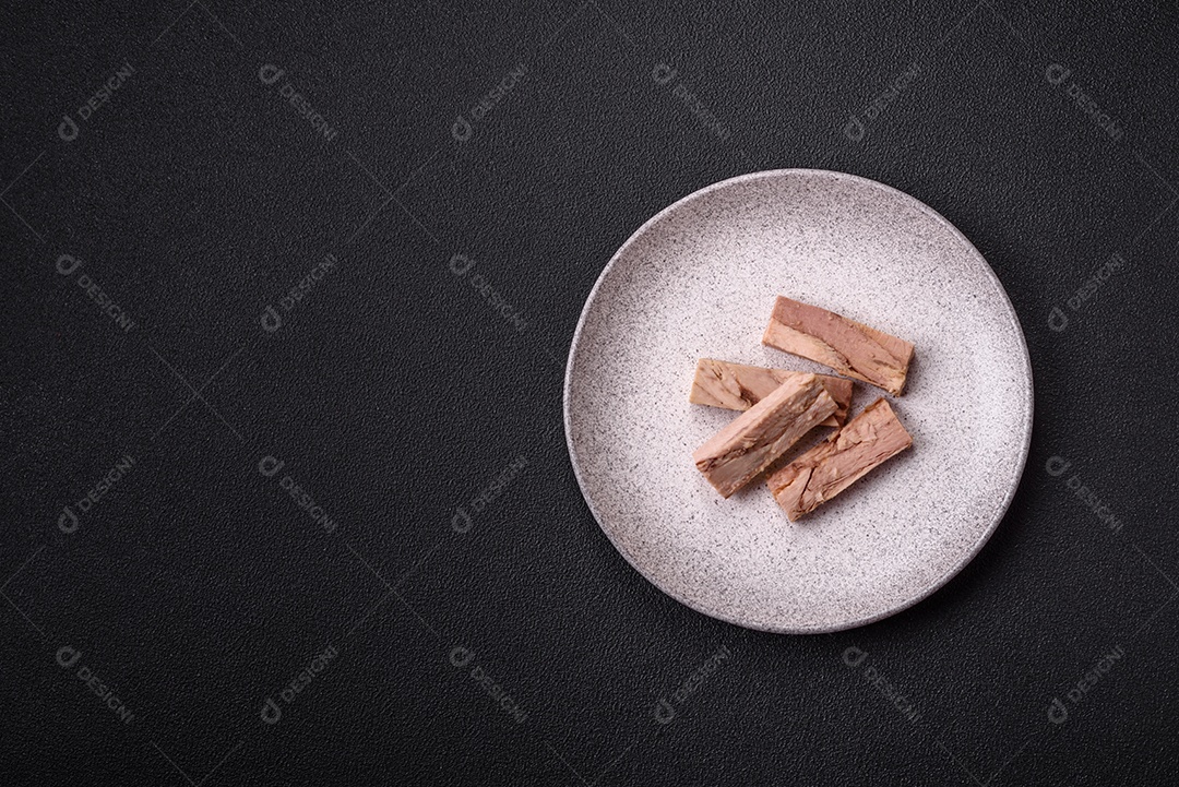 Deliciosa carne de atum dietético enlatado com sal, especiarias e óleo sobre um fundo escuro de concreto