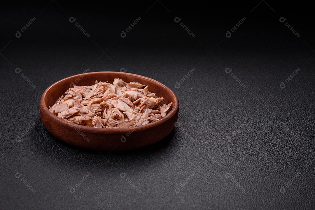 Deliciosa carne de atum dietético enlatado com sal, especiarias e óleo sobre um fundo escuro de concreto