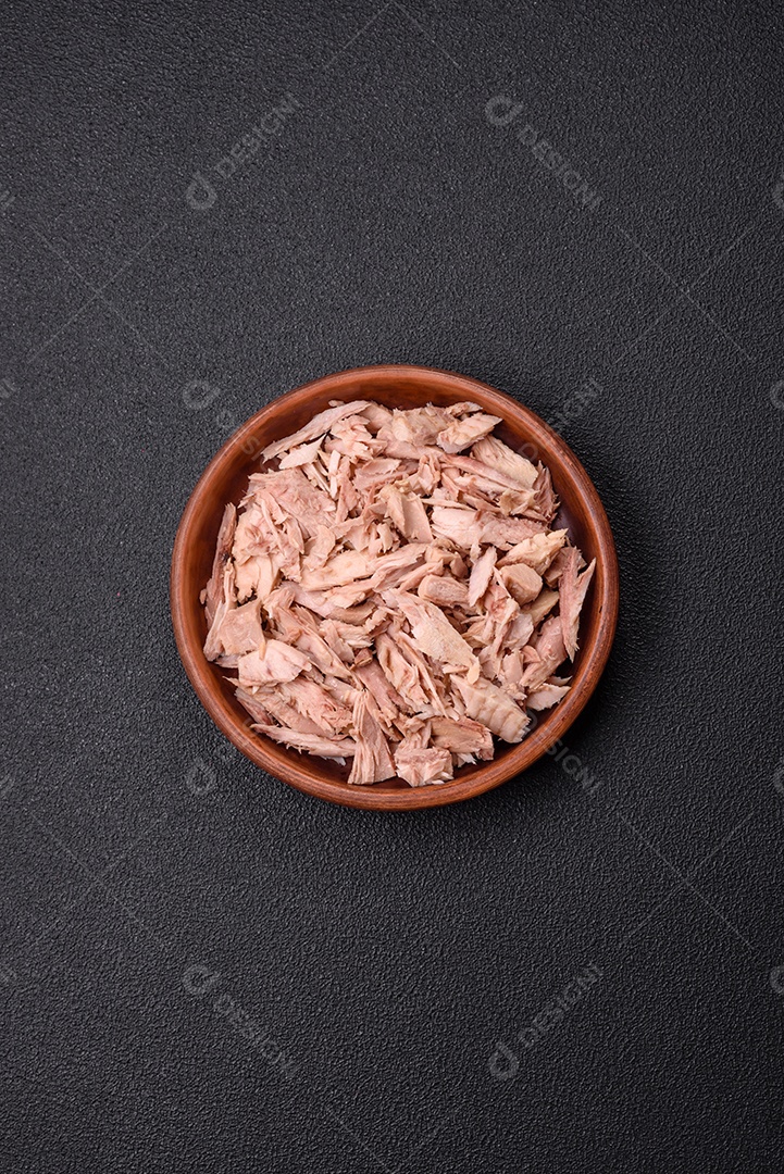 Deliciosa carne de atum dietético enlatado com sal, especiarias e óleo sobre um fundo escuro de concreto