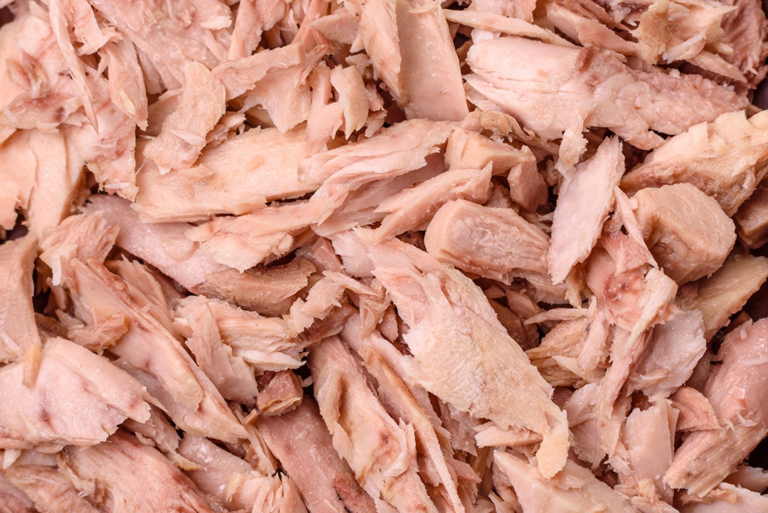 Deliciosa carne de atum dietético enlatado com sal, especiarias e óleo sobre um fundo escuro de concreto