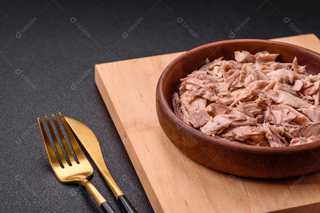 Deliciosa carne de atum dietético enlatado com sal, especiarias e óleo sobre um fundo escuro de concreto