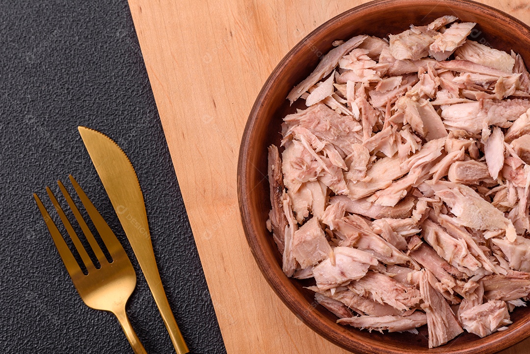 Deliciosa carne de atum dietético enlatado com sal, especiarias e óleo sobre um fundo escuro de concreto