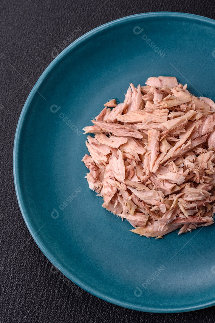 Deliciosa carne de atum dietético enlatado com sal, especiarias e óleo sobre um fundo escuro de concreto