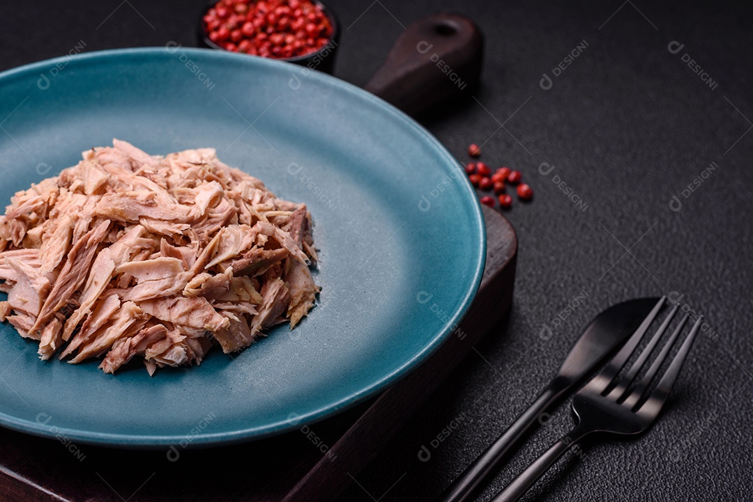 Deliciosa carne de atum dietético enlatado com sal, especiarias e óleo sobre um fundo escuro de concreto