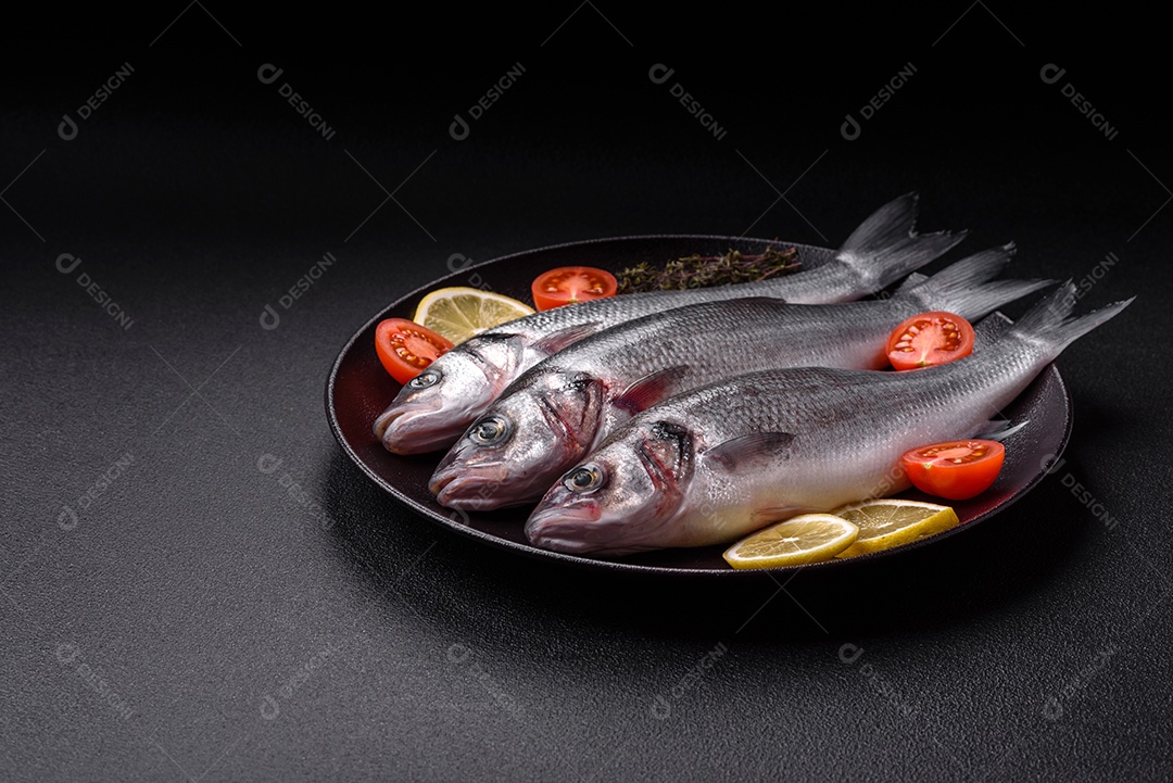 Peixe fresco de robalo oceânico cru com sal, especiarias e ervas em fundo de concreto escuro