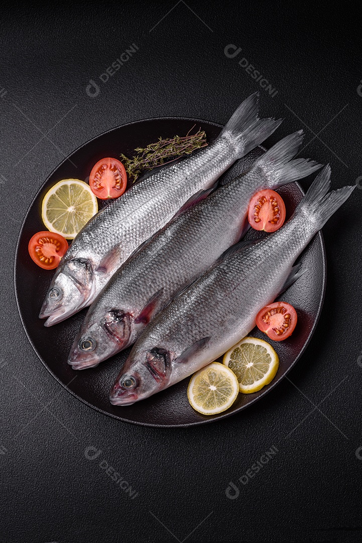 Peixe fresco de robalo oceânico cru com sal, especiarias e ervas em fundo de concreto escuro
