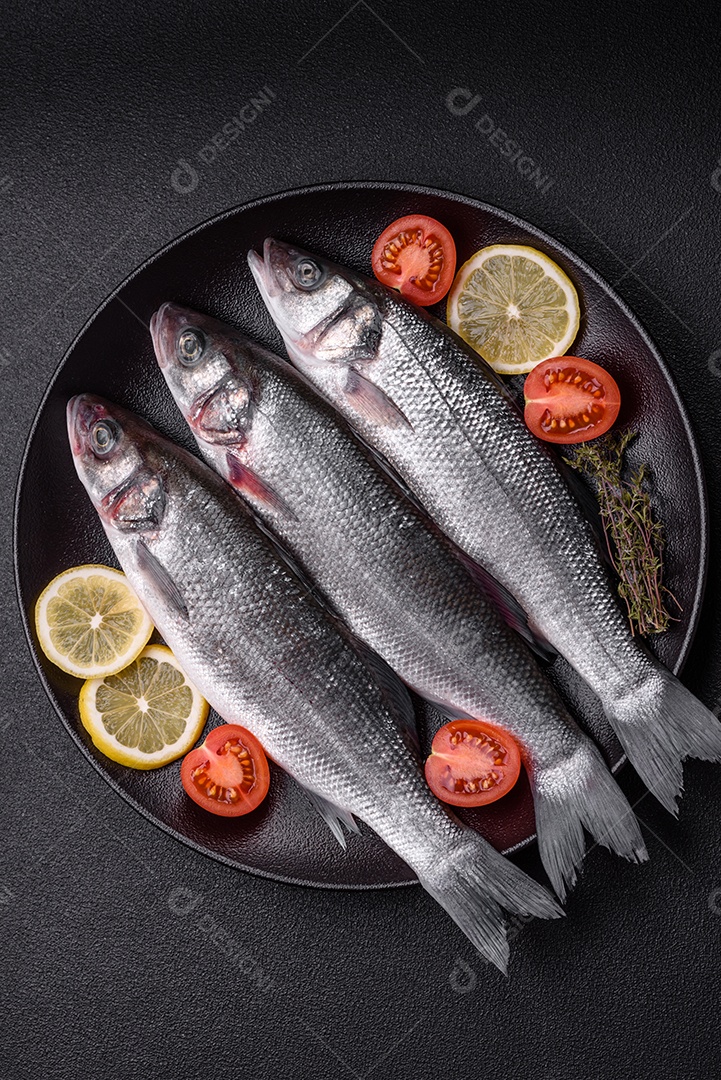 Peixe fresco de robalo oceânico cru com sal, especiarias e ervas em fundo de concreto escuro