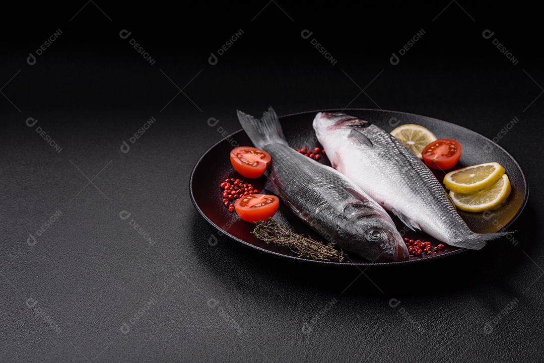 Peixe fresco de robalo oceânico cru com sal, especiarias e ervas em fundo de concreto escuro