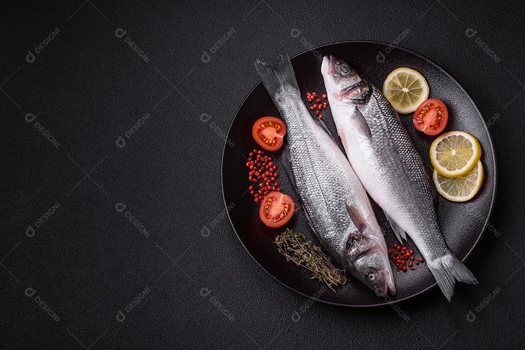 Peixe fresco de robalo oceânico cru com sal, especiarias e ervas em fundo de concreto escuro