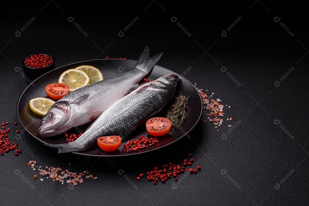 Peixe fresco de robalo oceânico cru com sal, especiarias e ervas em fundo de concreto escuro