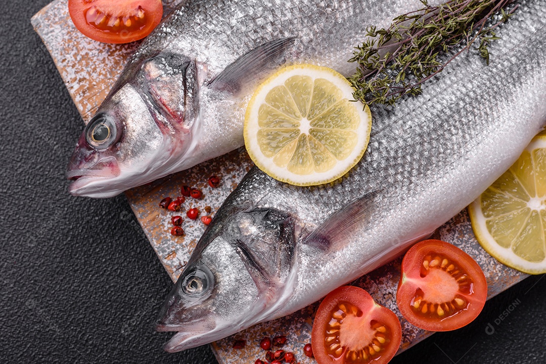 Peixe fresco de robalo oceânico cru com sal, especiarias e ervas em fundo de concreto escuro