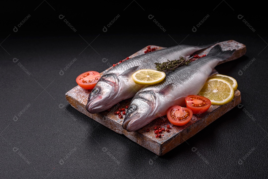 Peixe fresco de robalo oceânico cru com sal, especiarias e ervas em fundo de concreto escuro