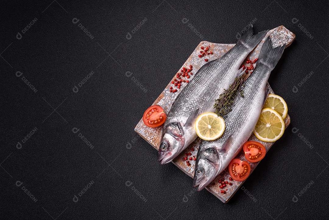 Peixe fresco de robalo oceânico cru com sal, especiarias e ervas em fundo de concreto escuro