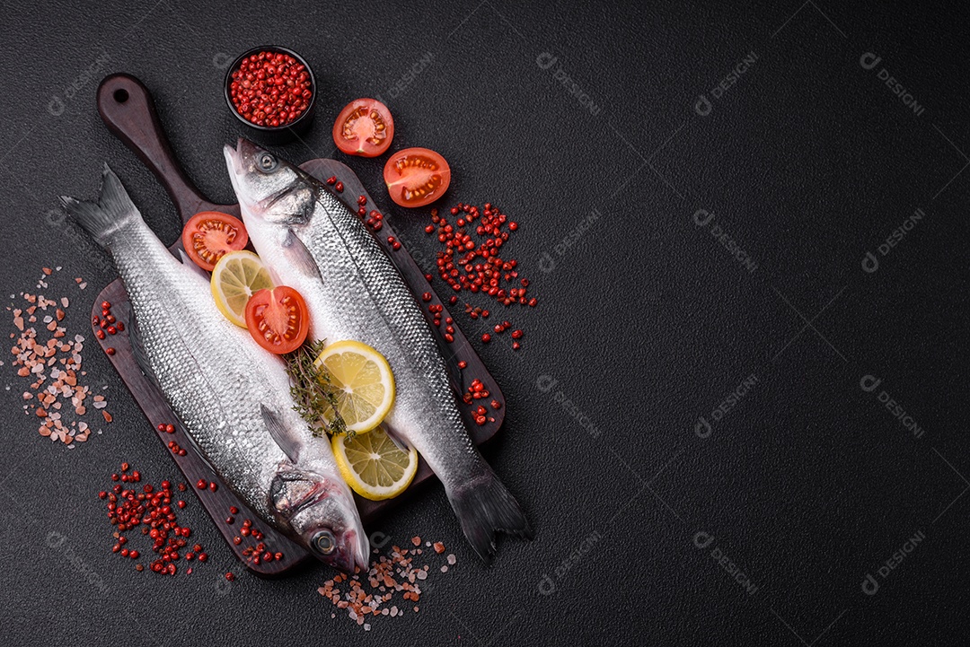 Peixe fresco de robalo oceânico cru com sal, especiarias e ervas em fundo de concreto escuro