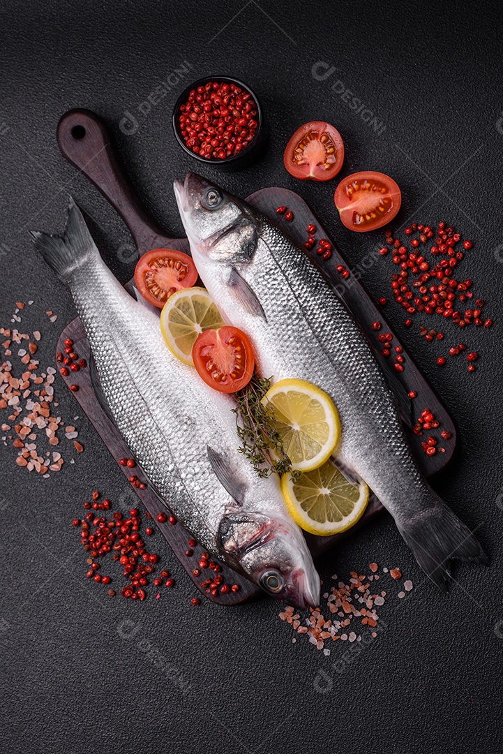 Peixe fresco de robalo oceânico cru com sal, especiarias e ervas em fundo de concreto escuro