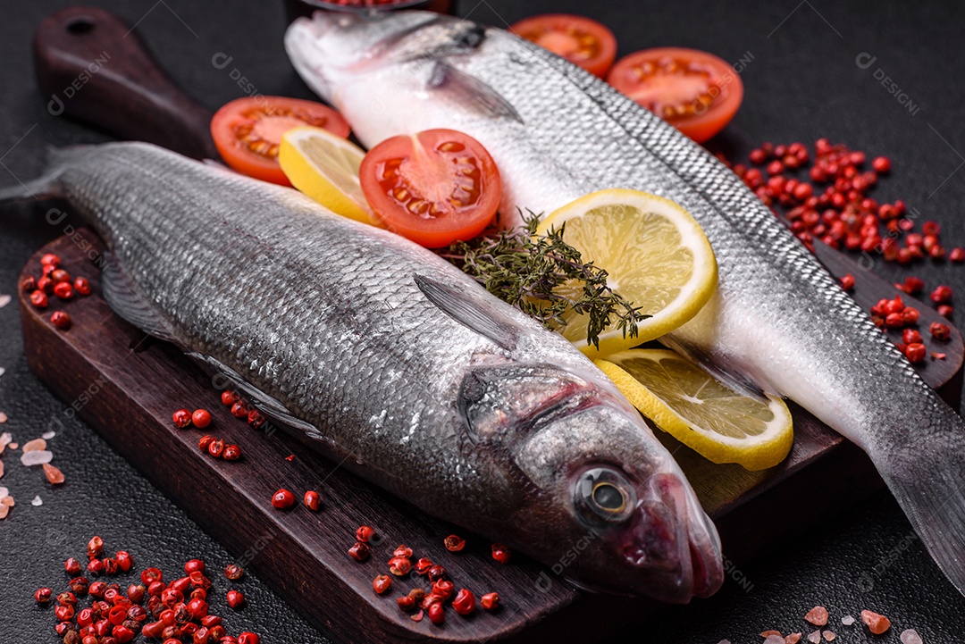 Peixe fresco de robalo oceânico cru com sal, especiarias e ervas em fundo de concreto escuro