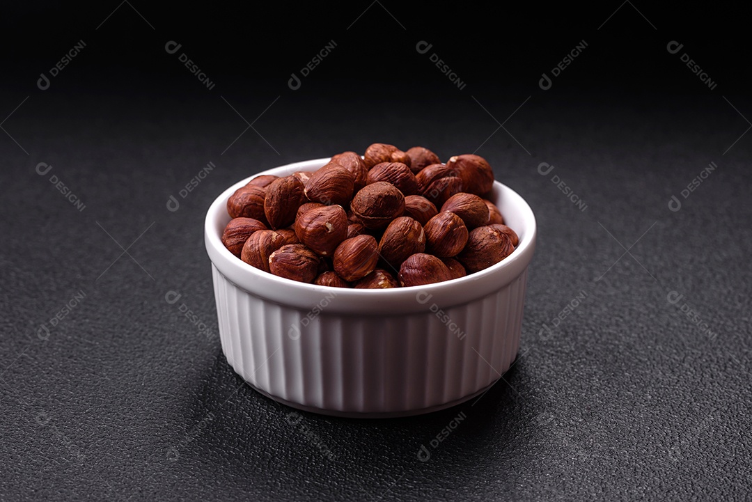 Deliciosa avelã inteira, crua, sem casca, sobre fundo escuro de concreto. Ingrediente calórico