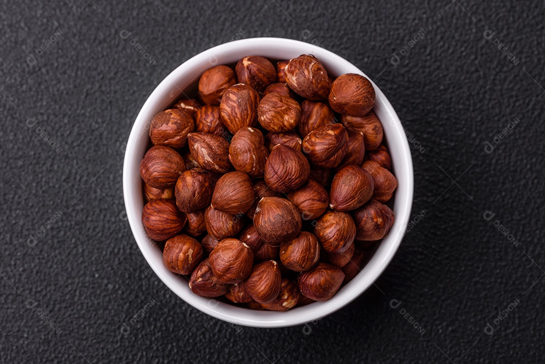 Deliciosa avelã inteira, crua, sem casca, sobre fundo escuro de concreto. Ingrediente calórico