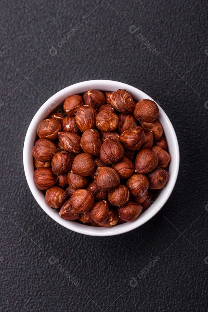 Deliciosa avelã inteira, crua, sem casca, sobre fundo escuro de concreto. Ingrediente calórico