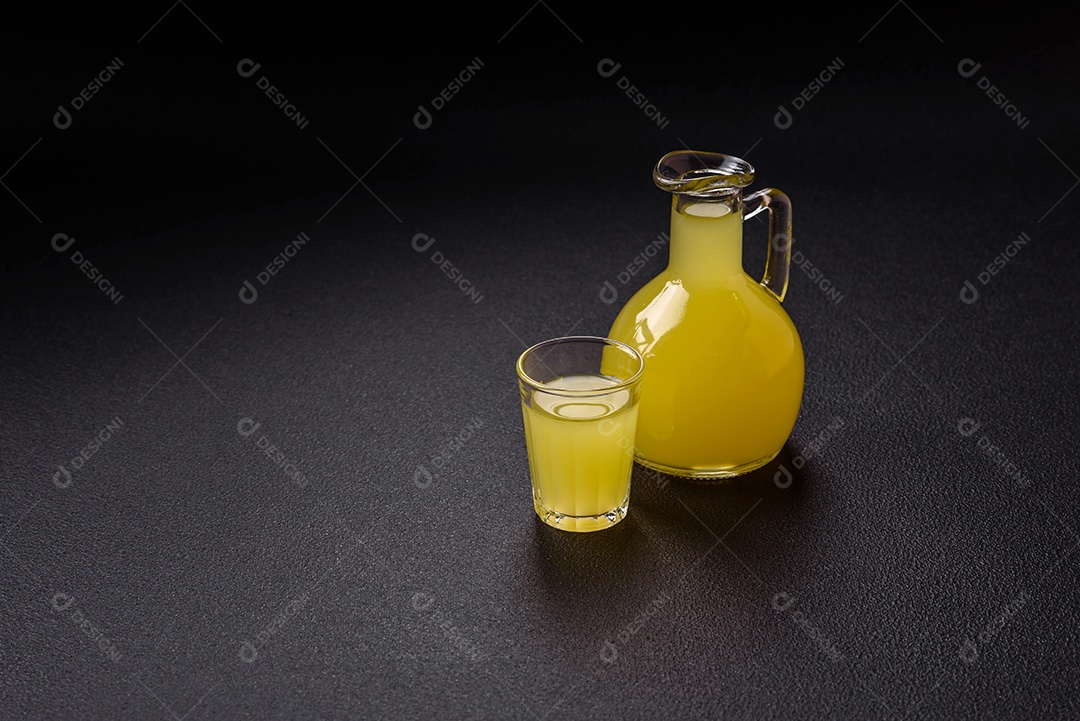 Bebida alcoólica limoncello amarelo em um copo pequeno sobre um fundo escuro de concreto